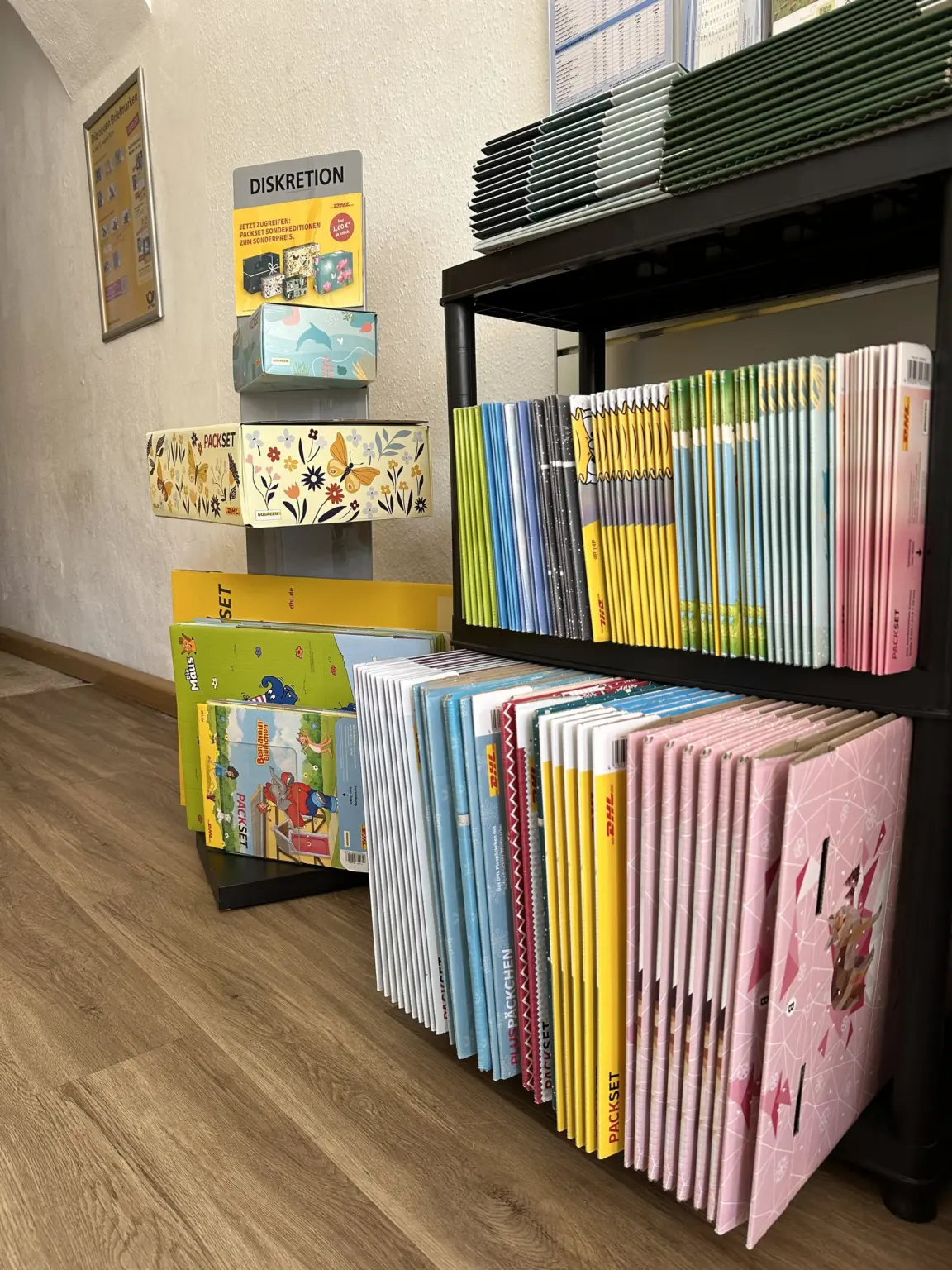 Postbereich im Laden am Markt mit DHL-Packsets in verschiedenen Größen, Versandtaschen und Hinweisschild „Diskretion“